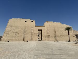 Front view of the first pylon of Ramesses III’s 20th-Dynasty mortuary temple at Medinet Habu in Luxor, with colossal victory reliefs flanking the central gateway