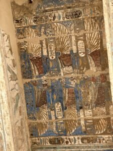 Painted ancient Egyptian ceiling panel with blue winged scarab motifs and royal cartouches at Medinet Habu