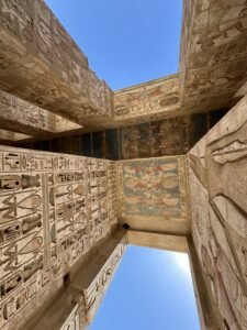 Painted hieroglyphic doorway and ceiling beams with surviving blue, red, and yellow pigment at Medinet Habu in Luxor, Egypt