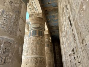 Narrow passage between hieroglyph-covered columns and walls with surviving blue pigment at Medinet Habu