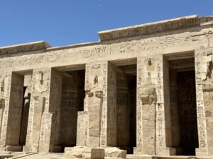 Stone columned facade at Medinet Habu with hieroglyphic inscriptions and painted columns visible inside