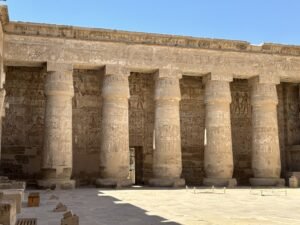 Row of massive carved stone columns along a sunlit court at Medinet Habu in Luxor