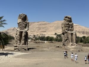 The two Colossi of Memnon statues of Amenhotep III standing before the Theban hills near Luxor