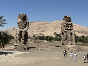 The two Colossi of Memnon statues of Amenhotep III standing before the Theban hills near Luxor
