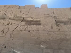Large ancient Egyptian battle relief carved across a temple wall at Medinet Habu in Luxor