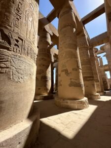 Tall carved sandstone columns in a sunlit hypostyle hall at Medinet Habu in Luxor