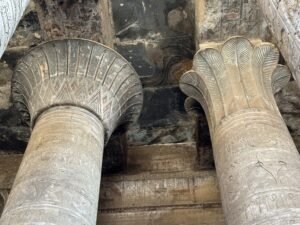 Ancient Egyptian columns with open floral capitals and carved hieroglyphs inside the Temple of Horus at Edfu, Egypt