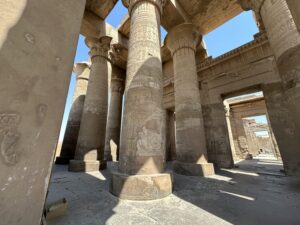 Ptolemaic hypostyle hall at Kom Ombo Temple with tall sandstone columns, composite floral capitals, royal cartouches, ritual scenes and hieroglyphic bands