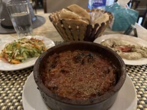 Egyptian meal with a baked clay-pot stew, salad, flatbread, and eggplant dip