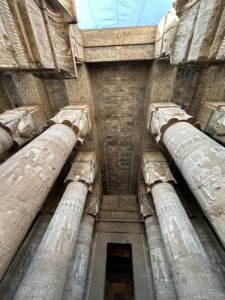 Tall Hathor-headed columns beneath the decorated ceiling of the Temple of Hathor at Dendera, Egypt