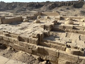 Ruined sandstone foundations and circular column bases within the Dendera Temple complex in Egypt