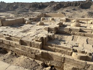 Ruined sandstone foundations and circular column bases within the Dendera Temple complex in Egypt