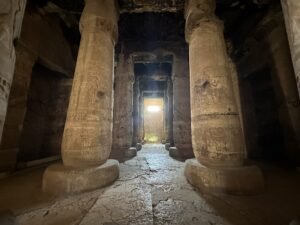 Carved stone columns lining a dark interior hall at the Temple of Seti I in Abydos, Egypt