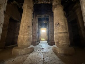 Rows of papyrus-bud sandstone columns carved with royal ritual scenes and hieroglyphs inside the hypostyle halls of Seti I’s temple at Abydos