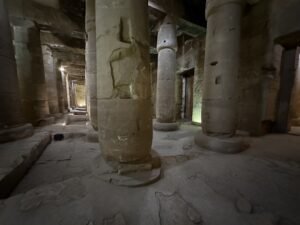 Ancient stone columns and carved figures inside a dim hall of the Temple of Seti I at Abydos, Egypt