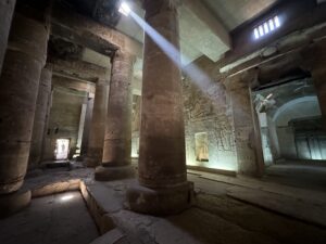 Dim column hall at the Temple of Seti I in Abydos, Egypt, with sunlight streaming through roof openings