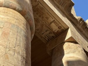 Ancient sandstone column and lintel with carved hieroglyphs and traces of color at Karnak Temple