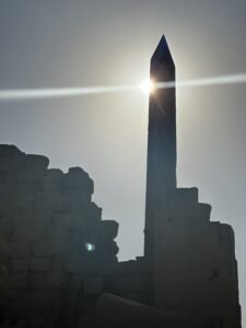 Ancient Egyptian obelisk at Karnak Temple silhouetted against the bright sun