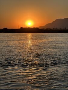 Orange sunset reflecting across the Nile River with the Theban hills silhouetted near Luxor