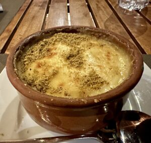 Warm Egyptian Umm Ali dessert baked in a clay pot with a creamy golden topping and crushed nuts