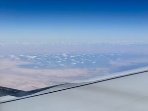 Aerial view from an airplane over Egypt’s desert landscape with scattered clouds and distant terrain