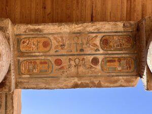 Two-register painted architrave at Karnak Temple with four royal cartouches, solar disks, ankhs, birds and hieroglyphic signs preserved in red, blue, green and yellow pigment