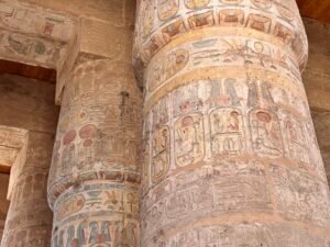 Massive Karnak Temple columns covered with painted hieroglyphs and ritual scenes in Luxor