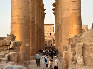 Visitors walking between the two rows of colossal papyrus columns in Amenhotep III's Great Colonnade at Luxor Temple in Luxor, Egypt