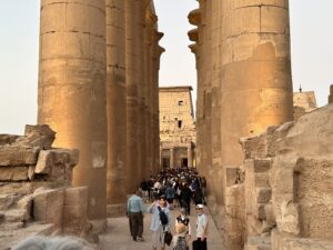 Visitors walking between the two rows of colossal papyrus columns in Amenhotep III's Great Colonnade at Luxor Temple in Luxor, Egypt