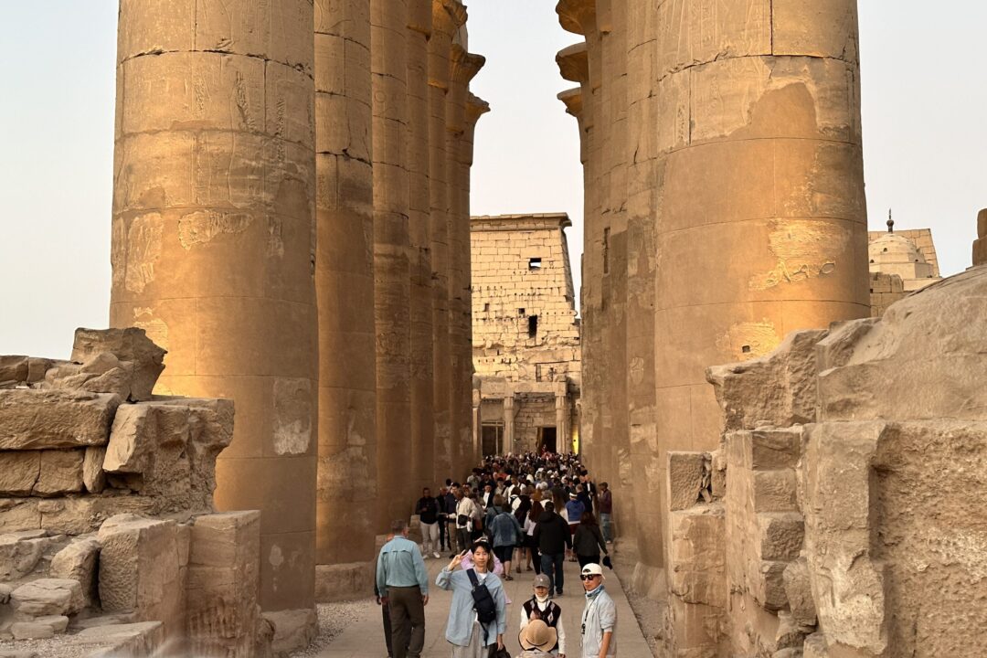 Visitors walking through the Great Colonnade of Amenhotep III at Luxor Temple