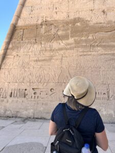 Visitor studying large Ptolemaic relief scenes and hieroglyphic inscriptions on a wall of the Temple of Horus at Edfu in Upper Egypt