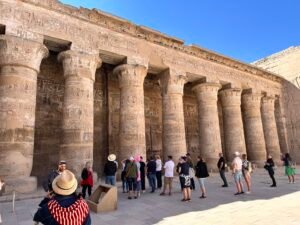 Visitors beside the decorated Ptolemaic columns of the first courtyard at the Temple of Horus at Edfu in Upper Egypt