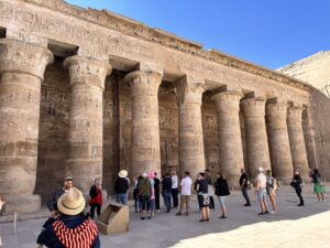 Visitors beside the decorated Ptolemaic columns of the first courtyard at the Temple of Horus at Edfu in Upper Egypt
