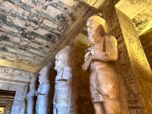 Row of Osiride pillars depicting Ramesses II inside the Great Temple at Abu Simbel beneath a painted ceiling