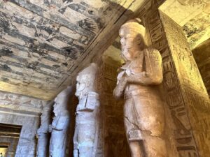 Row of Osiride pillars depicting Ramesses II inside the Great Temple at Abu Simbel beneath a painted ceiling