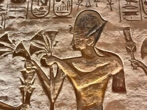 Carved relief of Ramesses II holding ritual objects at Abu Simbel with hieroglyphs and royal cartouches above