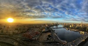 Panoramic sunrise over Cairo with the Nile River, bridges, city skyline, and Cairo Tower
