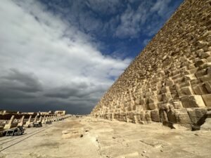 Massive limestone courses at the base of the Great Pyramid of Khufu beneath dramatic clouds on the Giza Plateau