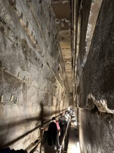 Visitors climbing the narrow stone Grand Gallery inside the Great Pyramid of Khufu at Giza