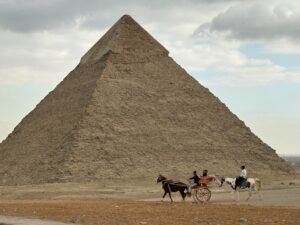 Pyramid of Khafre on the Giza Plateau with surviving casing stones near the summit as a horse-drawn carriage crosses the foreground