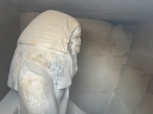 Side view of the seated statue of Pharaoh Djoser inside the serdab at Saqqara