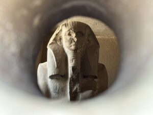 Seated statue of Pharaoh Djoser seen through a circular viewing hole in the Saqqara serdab