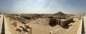 Wide panoramic view of excavated tombs, stone walls, and desert monuments across the Saqqara necropolis