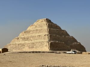 Step Pyramid of Djoser rising above the desert at Saqqara with a vehicle near its base
