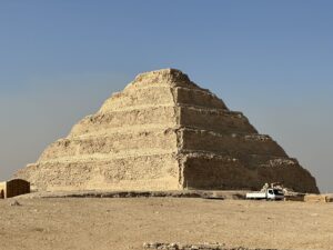 Step Pyramid of Djoser rising above the desert at Saqqara with a vehicle near its base