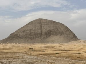 Weathered mudbrick Pyramid of Amenemhat III rising from the flat desert landscape at Hawara, Egypt