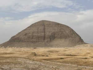 Weathered mudbrick Pyramid of Amenemhat III rising from the flat desert landscape at Hawara, Egypt