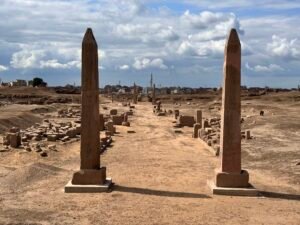 Two red granite obelisks of Pharaoh Ramesses II with hieroglyphic royal inscriptions framing the avenue of the Temple of Amun at Tanis in Egypt’s eastern Nile Delta