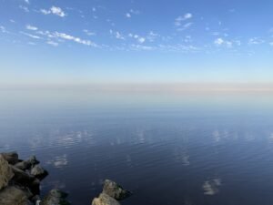 Calm blue Red Sea stretching to the horizon beneath a bright sky with small scattered clouds