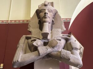 Upper portion of the sandstone colossus of Pharaoh Akhenaten, JE 49528, with crossed arms holding the heka and flail, nemes headdress, uraeus and surviving bases of tall Shu feathers, from his Aten precinct at East Karnak, Egyptian Museum Cairo